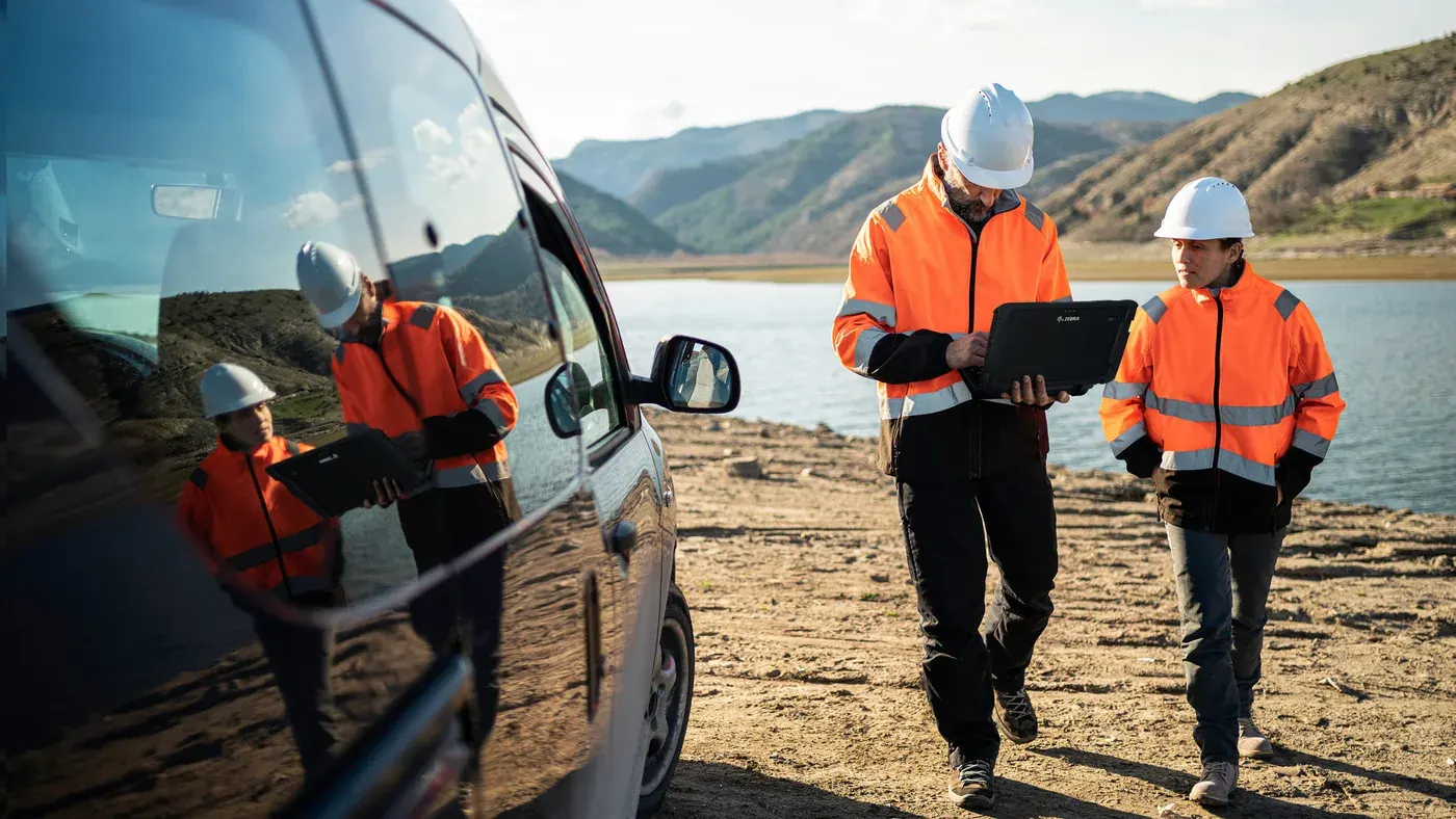 Two field engineers with a laptop walking beside a service van