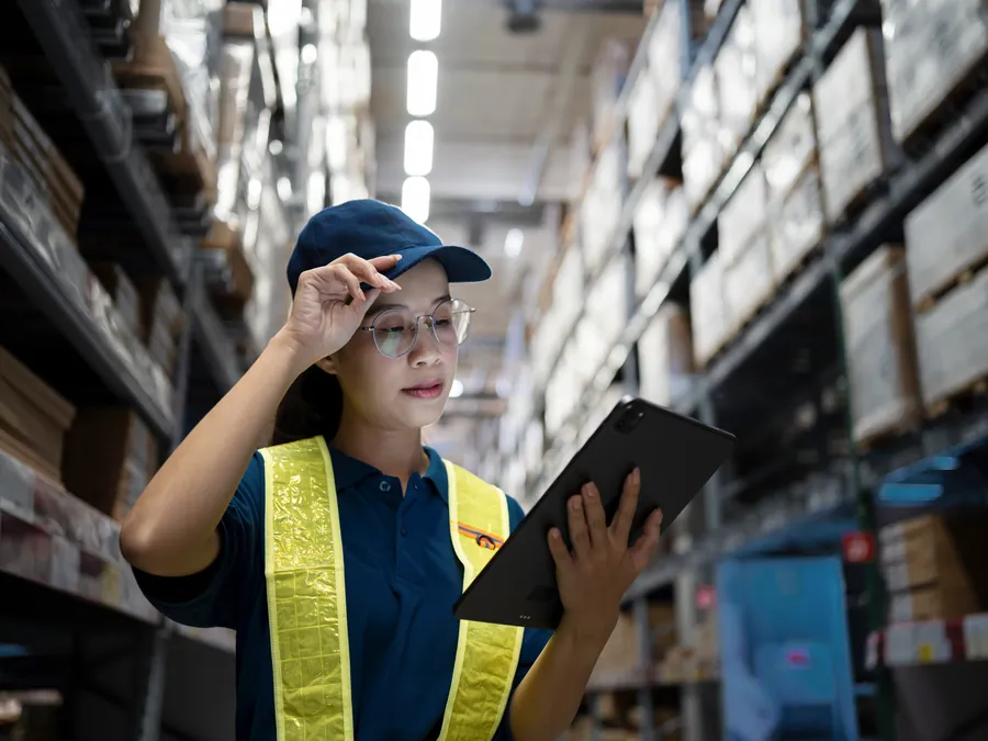 Warehouse worker in a safety vest checking stock with a tablet