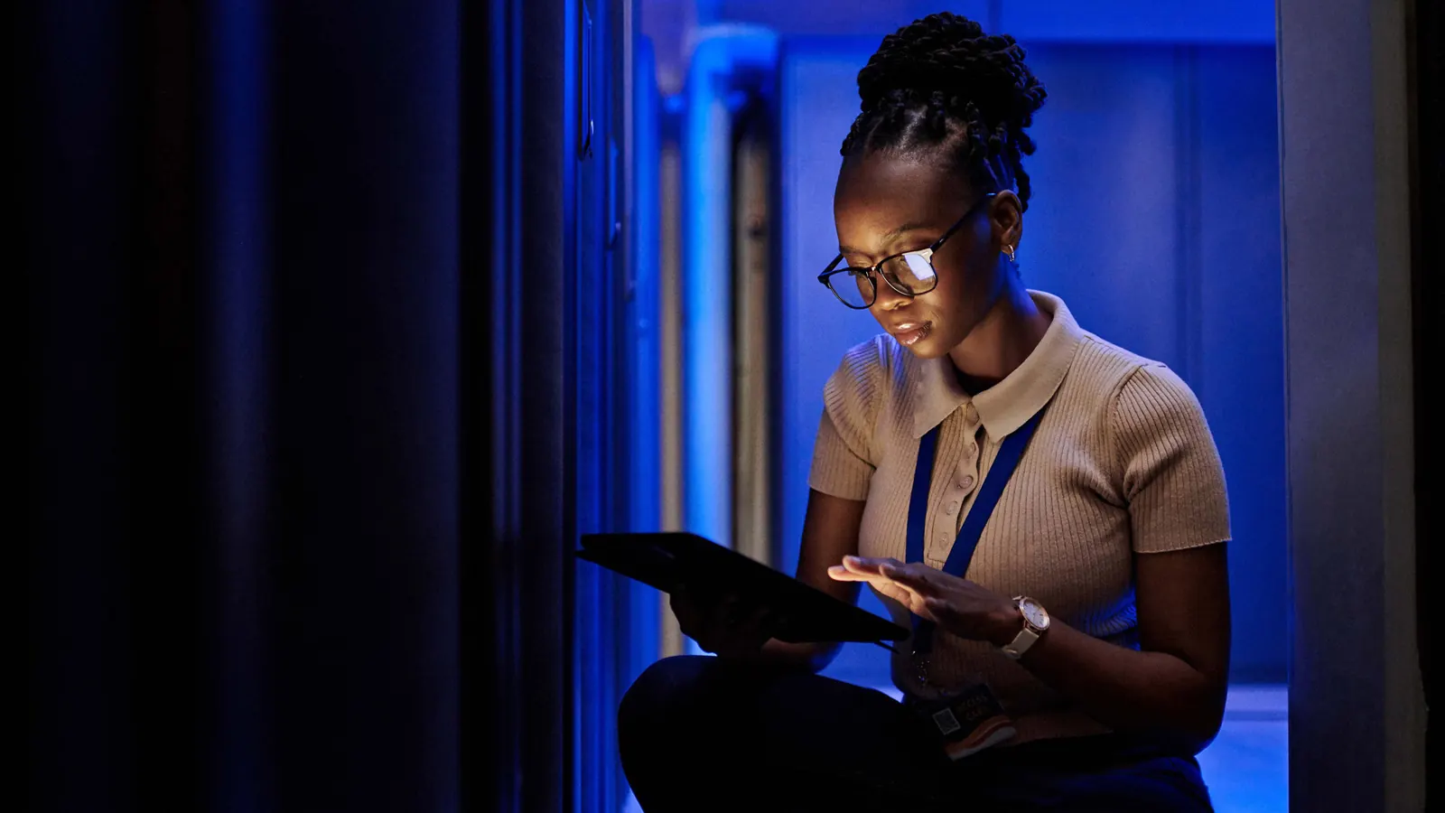 Technician checking a tablet in a server room as data syncs