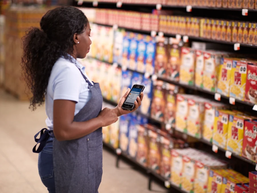 Retail store associate using a mobile computer beside grocery shelves