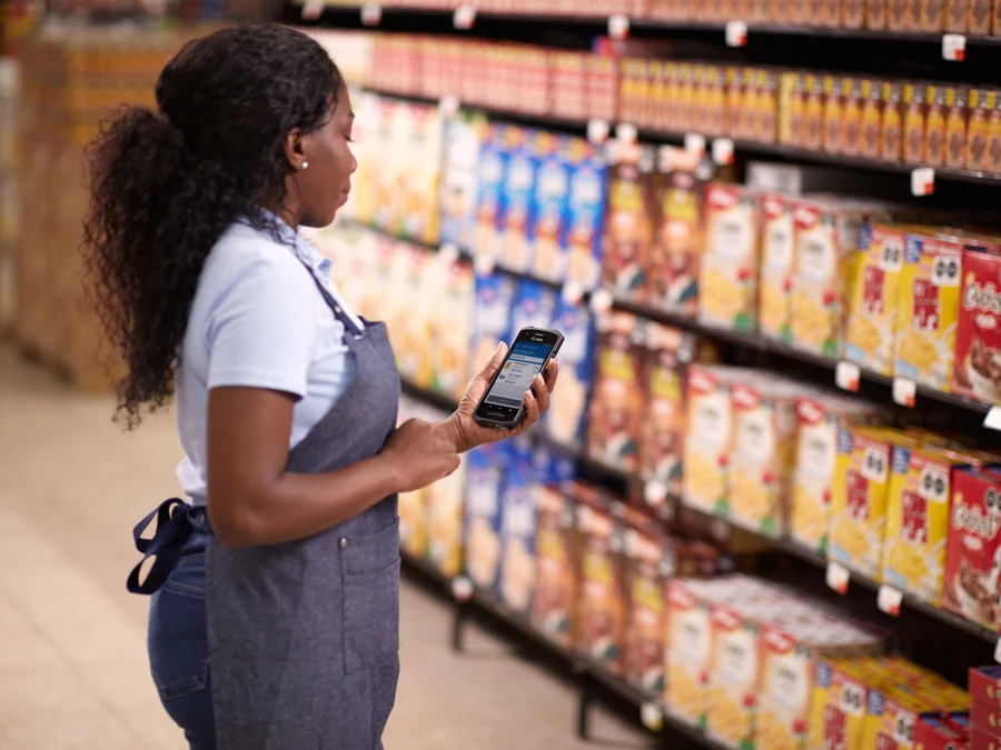 Store associate using a Zebra handheld among retail shelves