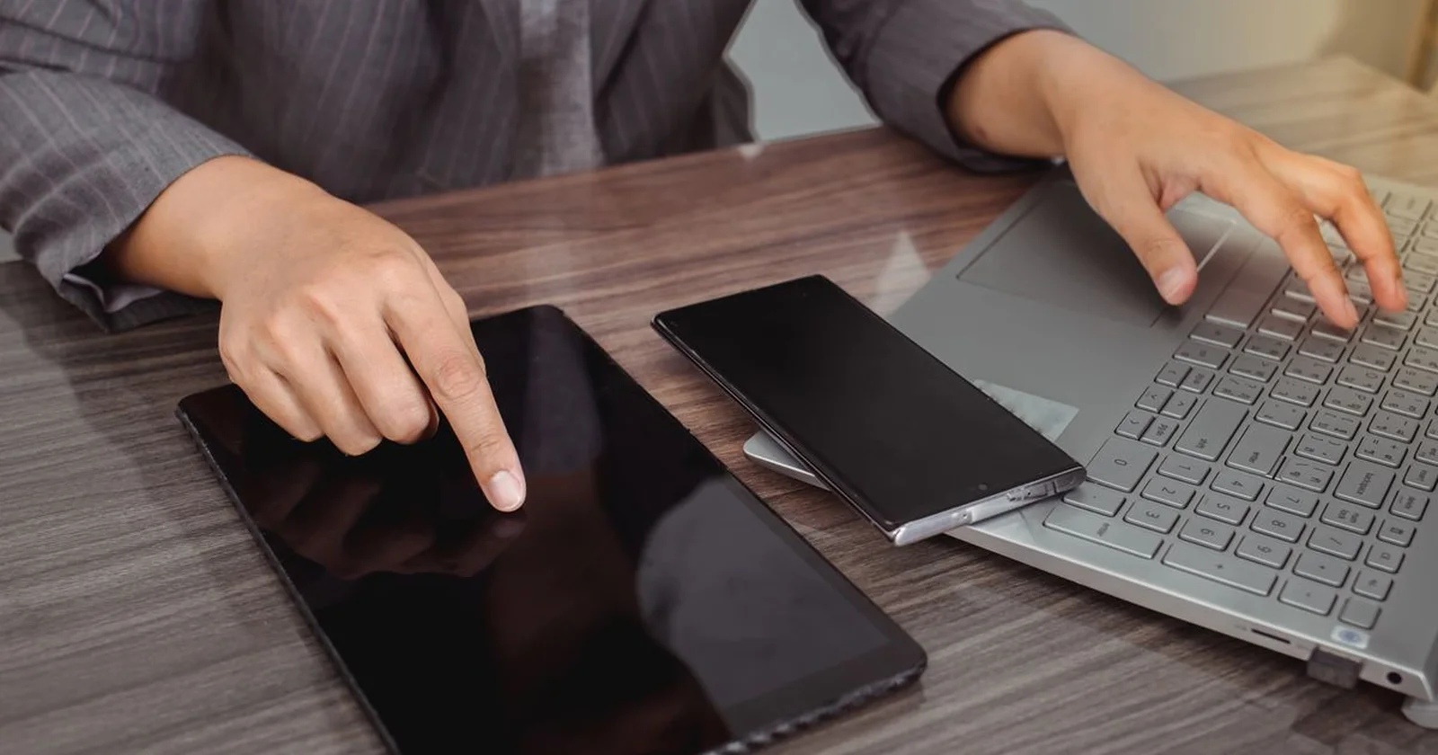 Tablet and laptop on a desk while device settings are checked.